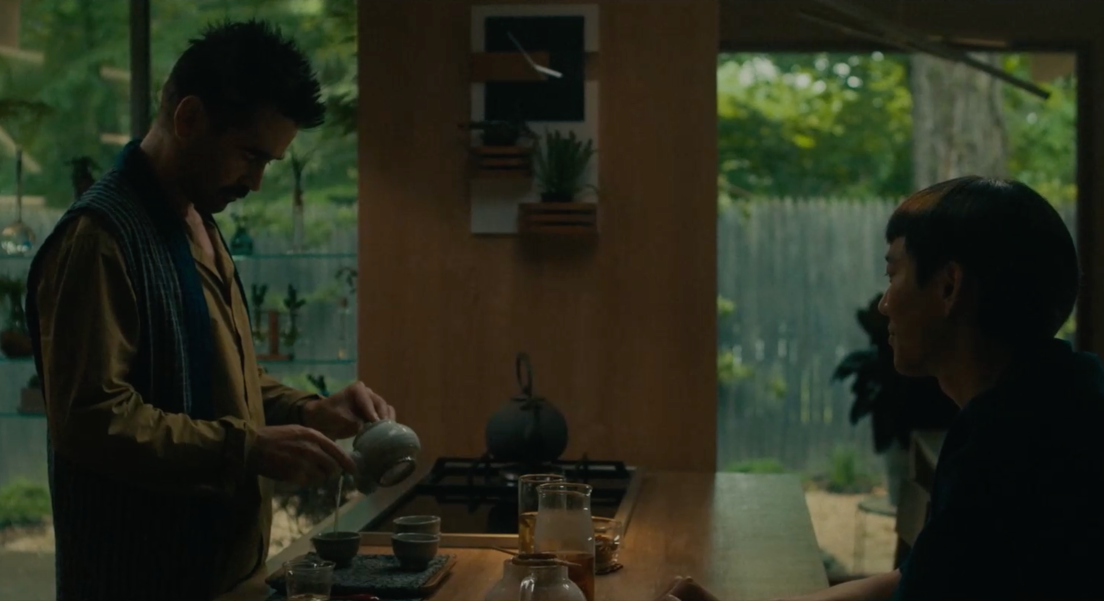 Jake prépare du thé qu'il verse dans une tasse. En face de lui, Yang le regarde. Ils se trouvent dans une cuisine, autour d'un plan de travail.