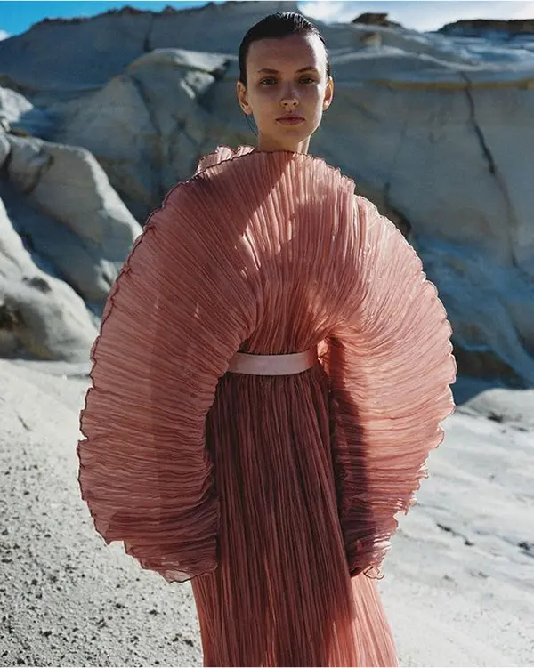 femme avec longue robe rose poupée fututriste, large volume au niveau des manches