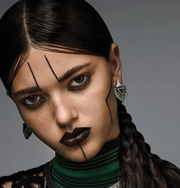 femme avec un makeup noir: lignes au niveau des yeux remontant sur son front et au niveau de la bouche, descendant sur son menton