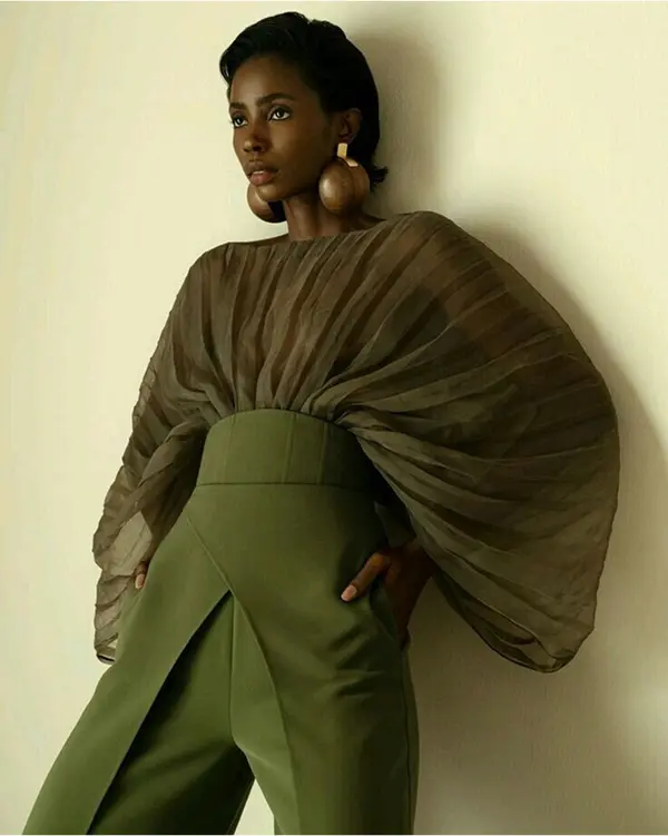 femme portant un pantalon vert et un top vert transparent, gros volume au niveau des manches